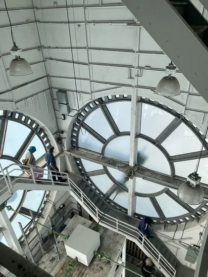 Interior of a heritage building showing large circular skylight windows and industrial-era metal walkways.