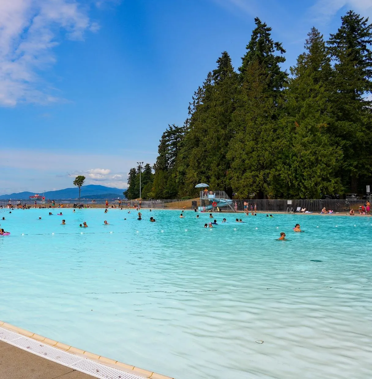 Second Beach Pool in Stanley Park — outdoor saltwater pool in active summer use with North Shore mountains in the background.