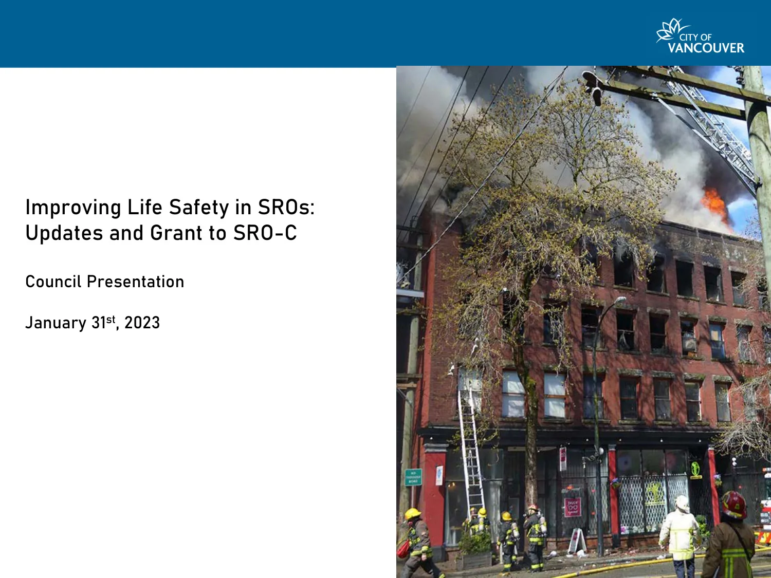 An SRO building in Vancouver actively burning, with firefighters responding on the street below.